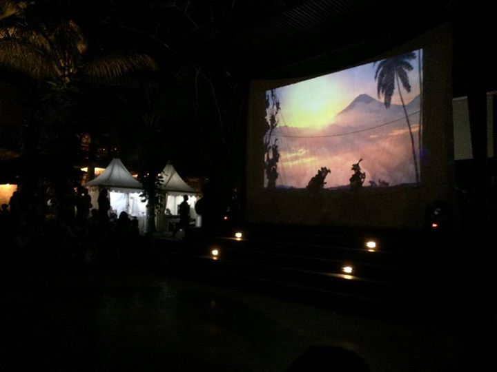 Projections create the scenery for the “clown of the left” Delem (r. on screen) in the Sanur Festival performance in 2022. 